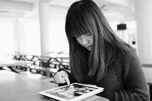 Asian woman reading text on an iPad