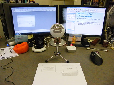 Desktop setup for an online presentation, with notes on two computer screens and a Blue microphone