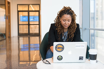 Black woman working on a laptop on a round table.